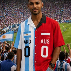 Pode incluir: Uma camisa de manga curta com um design dividido. Um lado apresenta as cores da bandeira argentina e o texto "ARG 0", enquanto o outro lado é vermelho com a bandeira austríaca e "AUS 0". A camisa tem uma gola preta.