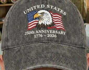 Puede incluir: Gorra de béisbol gris con las palabras "UNITED STATES" sobre una bandera americana y un águila. También muestra el texto "250th ANNIVERSARY 1776 - 2026". La gorra tiene una visera curva y una correa ajustable.