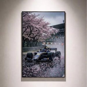 Puede incluir: Impresión enmarcada de un coche de carreras de Fórmula 1 en una pista mojada, con cerezos en flor en el fondo. El coche es azul oscuro y negro, con detalles amarillos. La imagen tiene un ambiente melancólico y atmosférico.