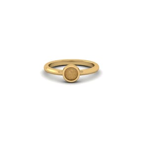 May include: A gold ring featuring a smooth, polished band and a central circular setting. The circular centerpiece has a textured, matte finish that contrasts with the shiny, reflective surface of the band, creating a simple, clean design.