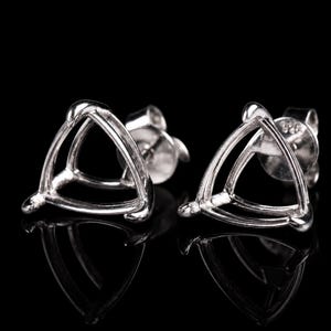Puede incluir: Un par de pendientes plateados. Cada pendiente presenta un diseño triangular con bordes redondeados. Los pendientes están sobre un fondo negro, con sus reflejos visibles debajo.