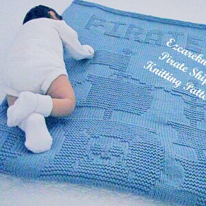 K&ouml;nnte beinhalten: Eine blaue gestrickte Babydecke mit einem Piratenschiff-Design. Die Decke ist mit einem strukturierten Stich gearbeitet und hat die Worte "Ezcareknits Pirate Ship Knitting Pattern" in der Ecke.
