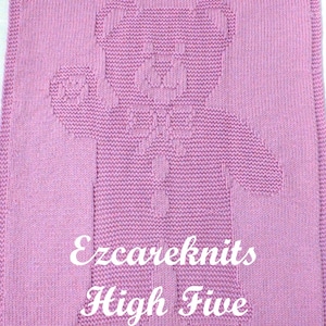 May include: A pink knitted baby blanket with a white bear design and the text "Ezcareknits High Five" in white.