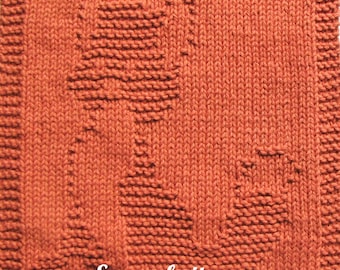May include: A knitted square in a burnt orange color features a textured design of a fox. The fox is created with raised stitches, adding dimension to the piece. The text "Ezcareknits Riley The Wiley" is at the bottom.