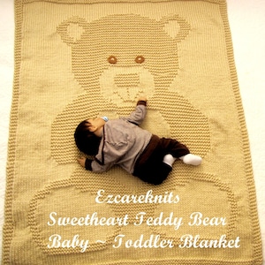 Puede incluir: Una manta de bebé de punto beige con un diseño de oso de peluche. La manta tiene forma rectangular con un borde. El texto "Ezcareknits Sweetheart Teddy Bear Baby ~ Toddler Blanket" se muestra en la manta.