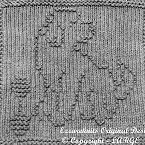 May include: A gray knitted dishcloth with a woven design of a heart and a flower. The dishcloth has the text "Ezcareknits Original Design © Copyright LARGE" at the bottom.