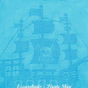 K&ouml;nnte beinhalten: Eine hellblaue gestrickte Babydecke mit einem wei&szlig;en gestrickten Piratenschiff-Design. Die Decke hat den Text "Pirate" oben und "Ezcareknits - Pirate Ship Knitting Pattern" unten.