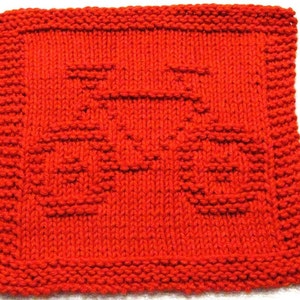 May include: A square, hand-knitted washcloth in a bright red hue. The washcloth showcases a repeating pattern of a smiling face. The edges are neatly finished with a ribbed border, adding texture and detail to the design. The washcloth is approximately 20 cm x 20 cm.