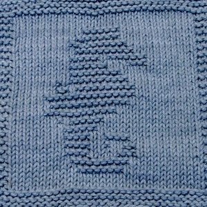 Könnte beinhalten: Ein quadratisches, gestricktes Textil in Hellblau. Die Mitte zeigt ein strukturiertes, stilisiertes Baumdesign. Die Ränder sind mit einem Rippenmuster eingefasst, das dem Stück einen definierten Rahmen verleiht. Die Gesamttextur ist weich und detailliert.