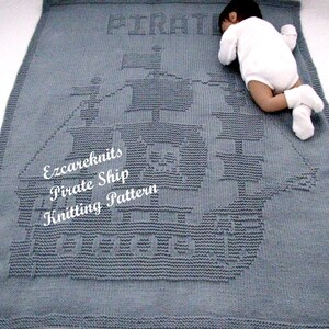 Könnte beinhalten: Eine graue gestrickte Babydecke mit einem gestrickten Piratenschiff-Design. Die Decke hat das Wort "Pirate" in die Oberseite der Decke gestrickt. Die Decke liegt auf einer weißen Oberfläche.