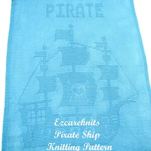 K&ouml;nnte beinhalten: Eine hellblaue gestrickte Babydecke mit einem wei&szlig;en gestrickten Piratenschiff-Design. Die Decke hat oben das Wort "Pirate" und unten den Text "Ezcareknits Pirate Ship Knitting Pattern".