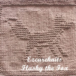 May include: A brown knitted dishcloth with a fox design. The dishcloth has the text "Ezcareknits Flashy the Fox" in white.