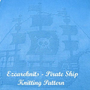 K&ouml;nnte beinhalten: Eine blaue gestrickte Babydecke mit einem wei&szlig;en gestrickten Piratenschiff-Design. Die Decke tr&auml;gt den Text "Ezcareknits - Pirate Ship Knitting Pattern" unten.