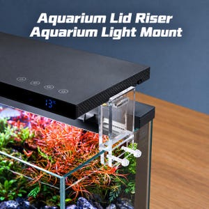 May include: A clear acrylic aquarium lid riser and light mount attached to the edge of a glass fish tank. The mount supports a black rectangular aquarium light fixture with a digital temperature display showing 13 degrees Celsius.
