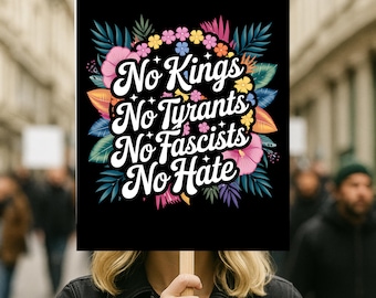 May include: A black sign with the words "No Kings, No Tyrants, No Fascists, No Hate" in white script, surrounded by colorful flowers and leaves. The sign is held up in a crowd of people.