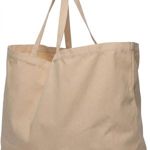 Op de afbeelding: Een grote, beige canvas draagtas met twee lange handvatten. De tas is rechthoekig met een brede opening en is gemaakt van een stevige, duurzame stof. De handvatten hebben dezelfde kleur als de tas.