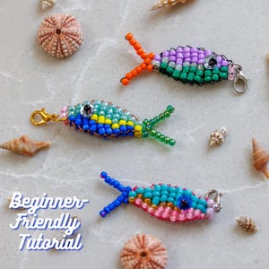 May include: Three beaded fish charms in blue, green, pink, and purple, with orange and green accents. The charms are made with small beads and have a clasp. The text "Beginner Friendly Tutorial" is also visible.