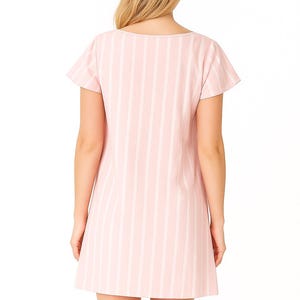 May include: A light pink and white striped dress with short sleeves. The dress has a scoop neckline and a simple, A-line silhouette. The model is facing away from the camera, showcasing the back of the dress. The dress is made of a lightweight fabric.