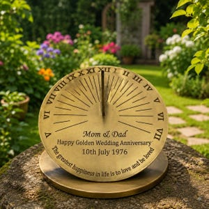 May include: A circular brass sundial featuring a central gnomon and Roman numerals from I to XII. The surface is engraved with the text: Mom & Dad, Happy Golden Wedding Anniversary, 10th July 1976, The greatest happiness in life is to love and be loved.