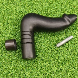 Puede incluir: Un mango negro y curvado con un agarre texturizado, un anillo de metal separado y un tornillo plateado. El mango está sobre una superficie de césped artificial verde. El mango tiene una forma única.