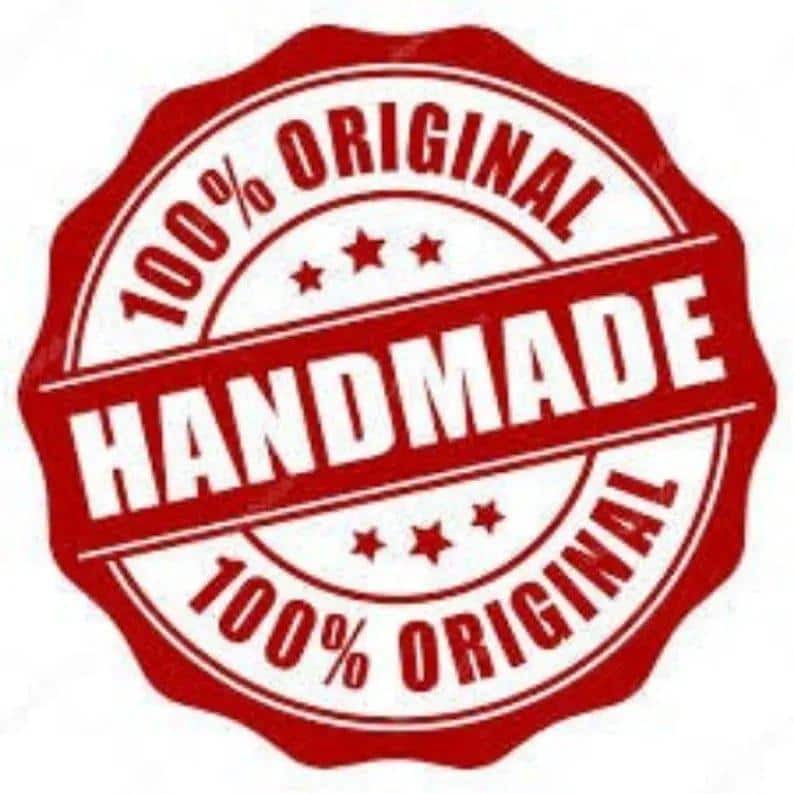 Op de afbeelding: Een rood en wit cirkelvormig embleem met de woorden "HANDMADE" en "ORIGINAL" in een vetgedrukte lettertype. De tekst "100%" is ook opgenomen. Het embleem heeft een geschulpte rand en drie kleine sterren.