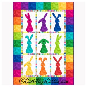 以下が含まれることがあります： 虹色の縁取りと白い中心部を持つカラフルなキルト。中心部には、9つのカラフルなウサギのシルエットが描かれています。キルトには「CastillejaCotton.com」の署名があります。