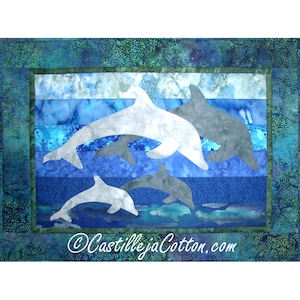 Puede incluir: Una colcha que representa tres delfines saltando fuera del agua. Los delfines son blancos y grises, y el agua es un degradado de colores azules. La colcha está enmarcada con un borde verde y tiene el texto "CastillejaCotton.com" en la esquina inferior derecha.