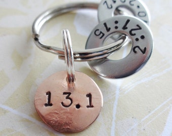 May include: A copper key chain with a round tag that says "13.1" and two silver key rings with the numbers "2:21:15" and "20:12" engraved on them.