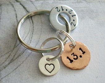 May include: Silver key chain with a heart charm, a round charm with the text "13.1", and a larger round charm with the text "2.12".