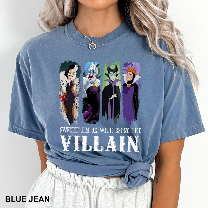 Puede incluir: Camiseta azul vaquero con cuatro personajes de villanos de dibujos animados. La camiseta tiene el texto blanco "SWEETIE I'M OK WITH BEING THE VILLAIN". La parte inferior de la camiseta tiene el texto "BLUE JEAN".