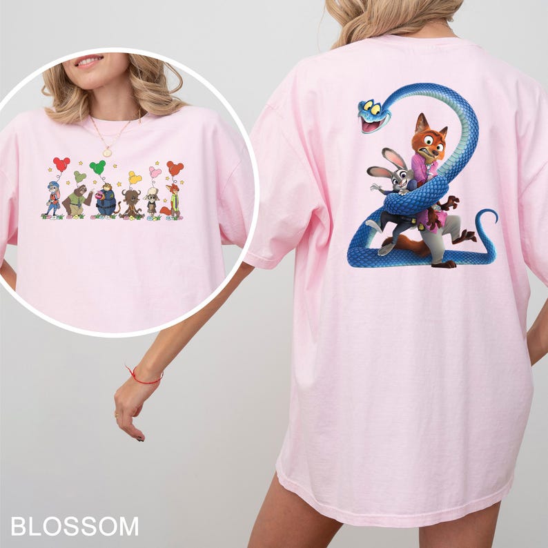 K&ouml;nnte beinhalten: Hellrosa T-Shirt mit Cartoon-Illustrationen auf Vorder- und R&uuml;ckseite. Die Vorderseite zeigt Cartoon-Charaktere mit herzf&ouml;rmigen Luftballons. Die R&uuml;ckseite zeigt eine blaue Schlange, die sich um Cartoon-Charaktere wickelt. Das Wort "BLOSSOM" steht unten.