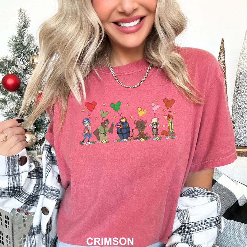 May include: Crimson t-shirt with a cartoon illustration of animal characters holding heart-shaped balloons. The text "CRIMSON" is printed at the bottom. The shirt has short sleeves and a crew neck. The colour is a deep red.