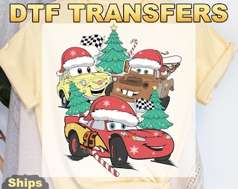 May include: A light yellow t-shirt featuring a DTF transfer design with cartoon cars wearing Santa hats and Christmas trees. The design includes the text "Ready To Press DTF TRANSFERS".