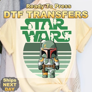May include: A light yellow t-shirt featuring a cartoon image of Boba Fett from Star Wars. The design includes the words "STAR WARS" in green, with the text "Ready To Press DTF TRANSFERS" at the top.