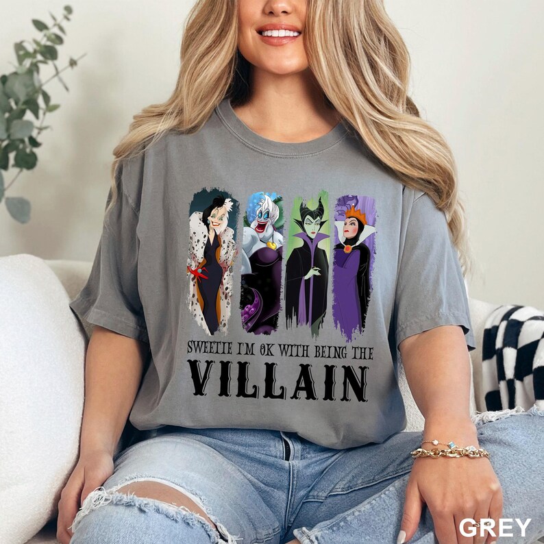 Puede incluir: Camiseta gris con un gr&aacute;fico de cuatro villanos de dibujos animados: Cruella de Vil, &Uacute;rsula, Mal&eacute;fica y la Reina Malvada. El texto "Sweetie I'm OK with being the Villain" est&aacute; impreso debajo.