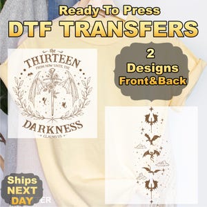 May include: Cream-colored DTF transfer designs with text that reads "Ready To Press DTF TRANSFERS". The shirt features two designs: one with a sword and wings, and another with dragon-like figures. The text "the THIRTEEN DARKNESS CLAIMS US +" is also visible.