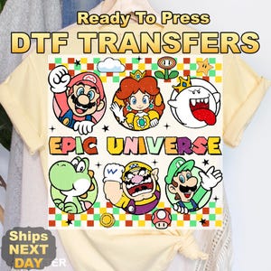 May include: A light yellow t-shirt featuring a colorful graphic of various characters from the Epic Universe. The text "Ready To Press DTF TRANSFERS" and "EPIC UNIVERSE" are printed on the shirt. The shirt is knotted at the bottom.