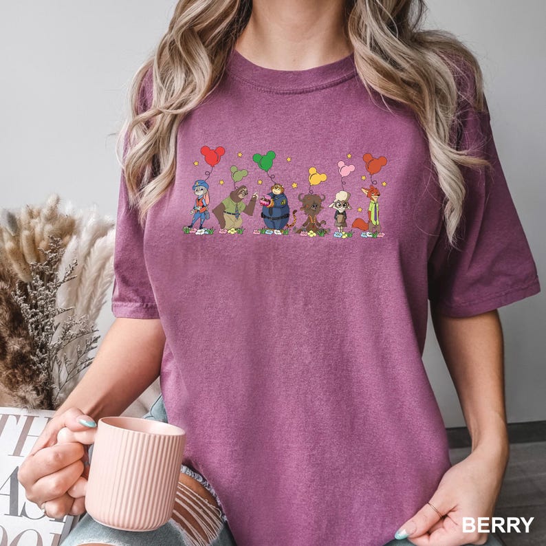 May include: Berry-coloured t-shirt with a cartoon design of animal characters holding heart-shaped balloons. The characters stand on flowers. The word "BERRY" is printed in white at the bottom right of the shirt.