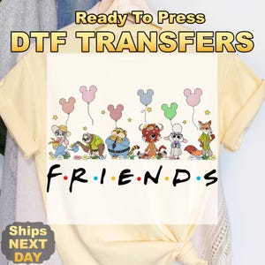 May include: Cream-colored t-shirt featuring a cartoon design of animal characters holding Mickey Mouse-shaped balloons. The word "FRIENDS" is written in a black font. The text "Ready To Press DTF TRANSFERS" is at the top.