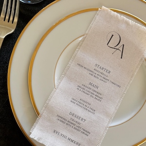 May include: A white ceramic mug with a black handle and the text "But First, Coffee" in a black, handwritten-style font. The mug is on a white surface.