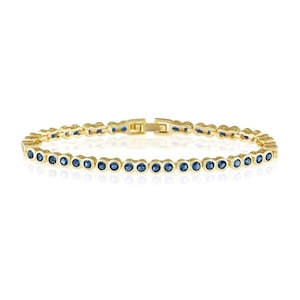 Könnte beinhalten: Ein goldfarbenes Armband mit einer Reihe runder, dunkelblauer Edelsteine. Das Armband hat ein klassisches Design mit einem sicheren Verschluss. Die Edelsteine sind gleichmäßig über die Länge des Armbands verteilt.