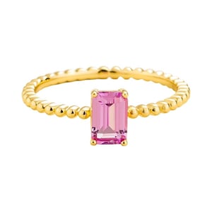 Könnte beinhalten: Goldfarbener Ring mit einem rosa, rechteckigen Edelstein in der Mitte. Das Band hat ein Perlendesign. Der Ring ist ein Schmuckstück.