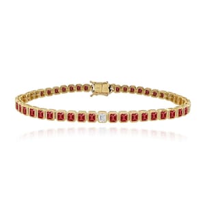 Könnte beinhalten: Ein goldfarbenes Armband mit einer Reihe rechteckiger roter Edelsteine, die von einem einzelnen, rechteckigen, klaren Edelstein unterbrochen werden. Das Armband hat einen Verschluss und ist wahrscheinlich aus Gold gefertigt. Die Edelsteine sind in einer Lünettenfassung gefasst.