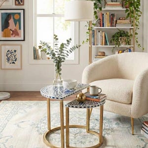 May include: A white ceramic mug with a black handle and the text "But First, Coffee" in a black, handwritten-style font. The mug is on a white surface.