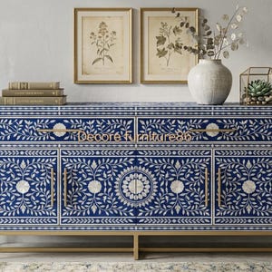 May include: A rectangular sideboard featuring a deep blue and white floral inlay pattern across its front. The piece includes two top drawers and four cabinet doors with gold-toned metal handles and a matching gold-toned metal base frame.