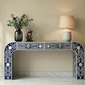 May include: A navy blue and white console table with floral inlay design. The table has two drawers with decorative knobs and curved legs. A lamp, vase, and sculpture are on top of the table.