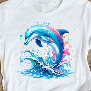 May include: White t-shirt featuring a vibrant illustration of a dolphin leaping out of blue waves. The dolphin is depicted in shades of blue, pink, and white, with colorful splashes around it. The design is a playful and eye-catching graphic.