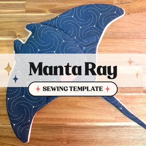 Könnte beinhalten: Eine blaue Manta-Rochen-Nähvorlage mit weißem Punktmuster. Der Text "Manta Ray" wird fett dargestellt, darunter "SEWING TEMPLATE". Die Vorlage befindet sich auf einer Holzoberfläche.