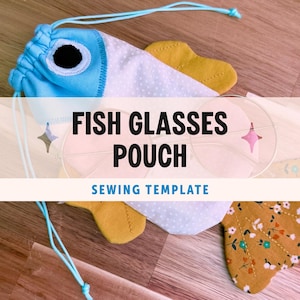 Op de afbeelding: Een visvormig brillenzakje met trekkoord, een lichtblauwe kop met een zwart-wit oog, een wit lichaam met kleine stippen en mosterdgele vinnen. De tekst FISH GLASSES POUCH SEWING TEMPLATE is over het zakje heen geplaatst.