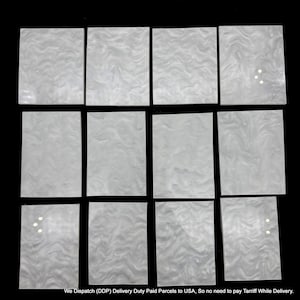 May include: Twelve rectangular pieces of white acrylic material arranged in a grid. Each piece features a smooth, glossy surface with a subtle, swirling marbled pattern in varying shades of white and light grey, creating a uniform appearance.